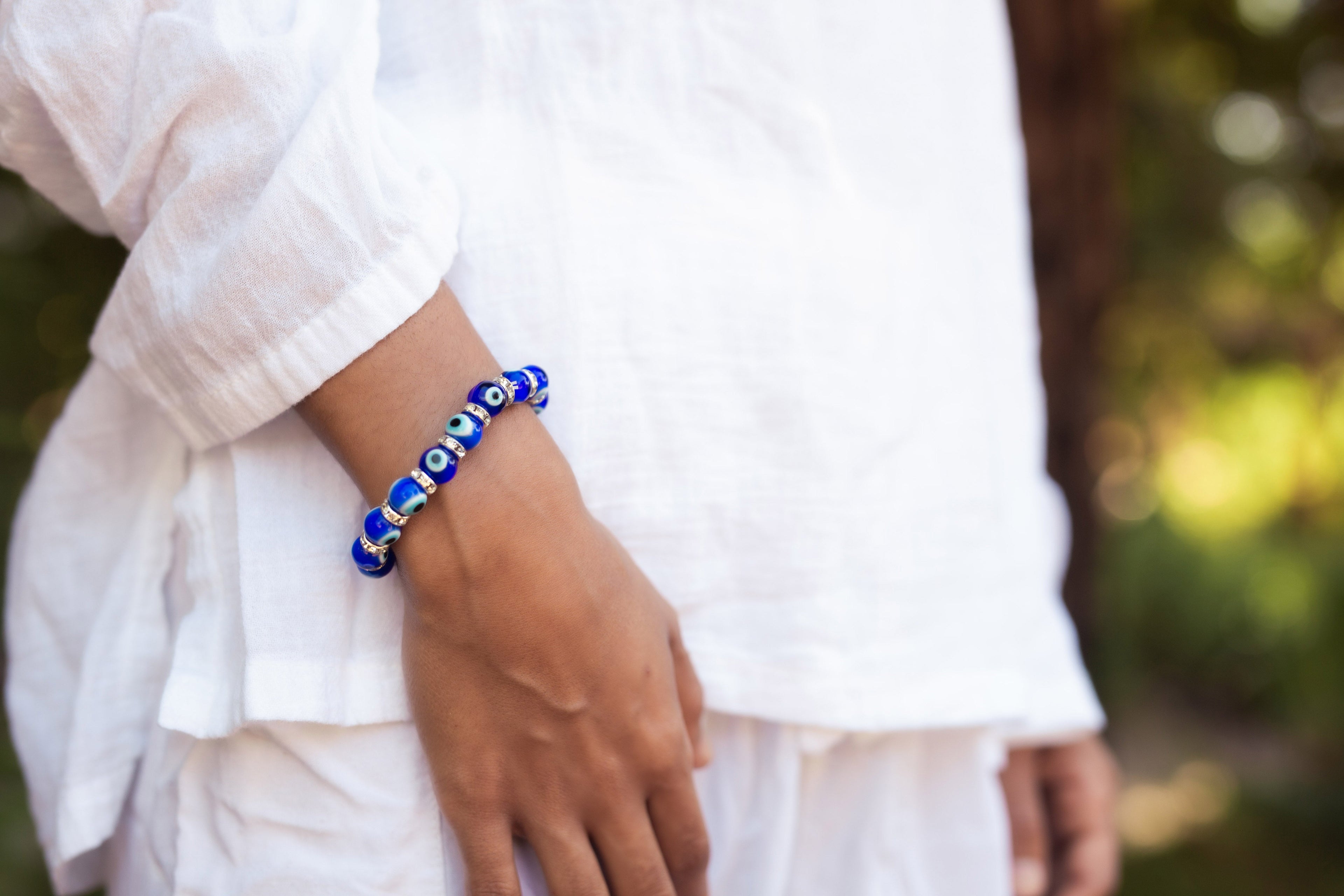 Person wearing a blue beaded bracelet on a blurred natural background