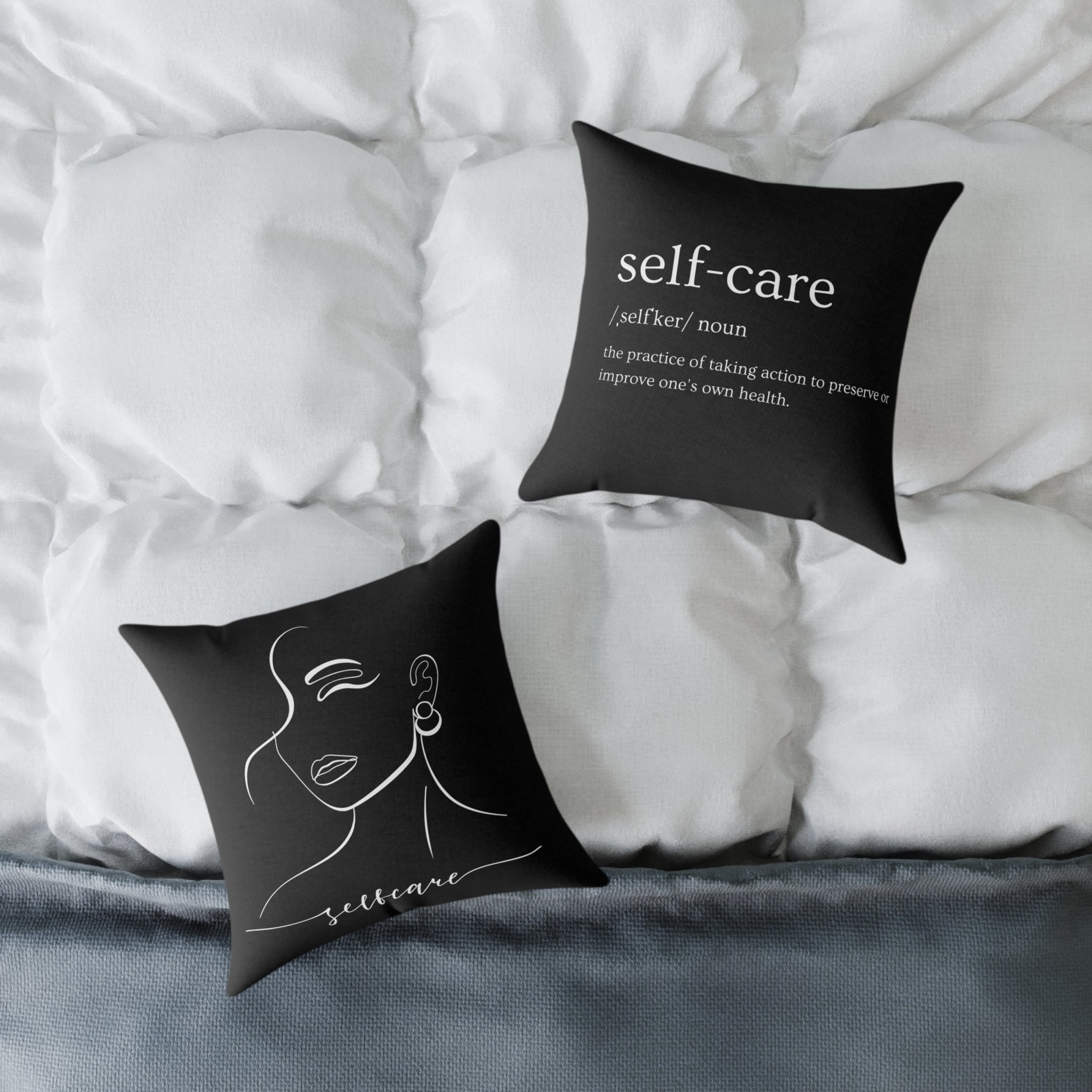 Two black pillows with 'self-care' definitions on a bed