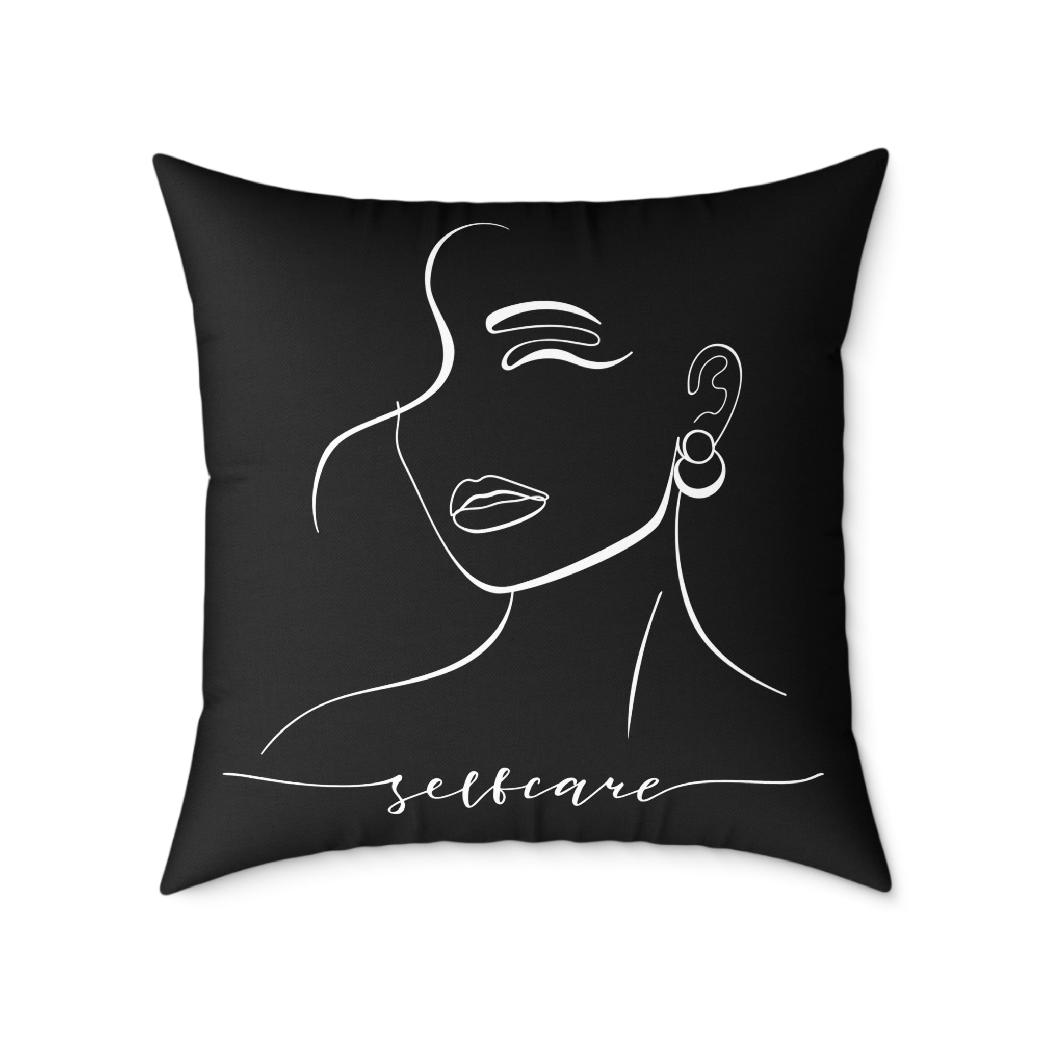 Black pillow with white line art of a face and 'selfcare' text on a white background