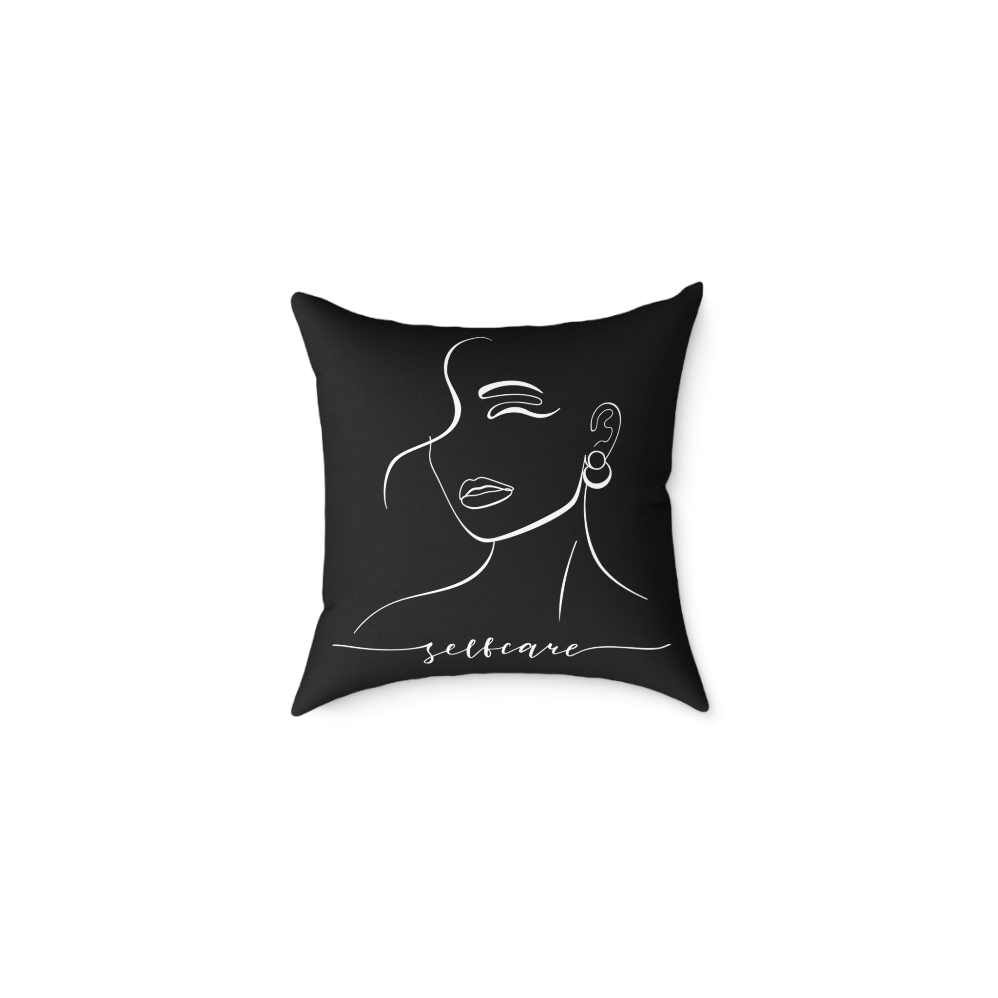 Black pillow with a white line drawing of a face and the word 'selfcare'