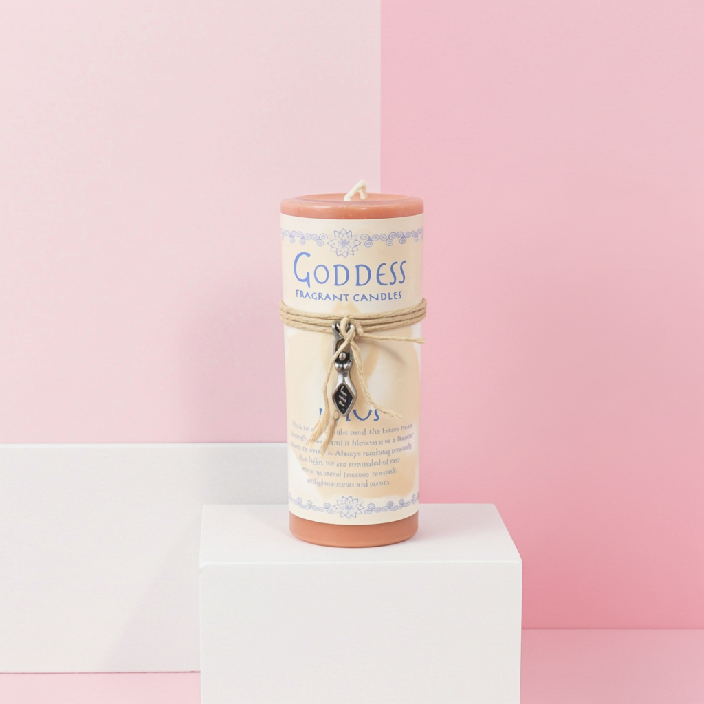 A cylindrical scented candle labeled 'Goddess Fragrant Candle' with a peach-colored top and base, cream label, and a small hanging charm, displayed on a white pedestal against a pink and light gray background.