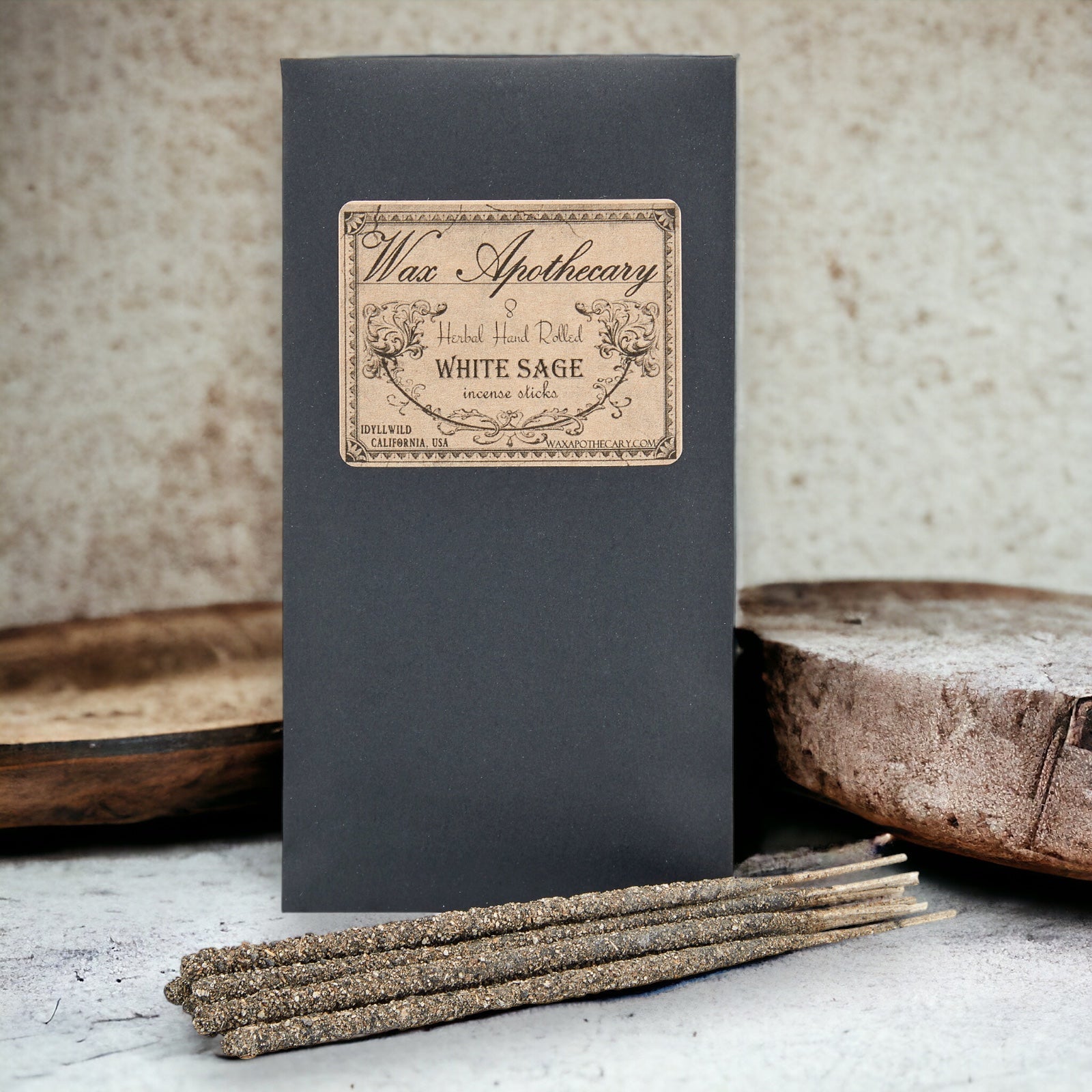 Dark gray box with 'Wax Apothecary' label and white sage incense sticks on a textured surface.