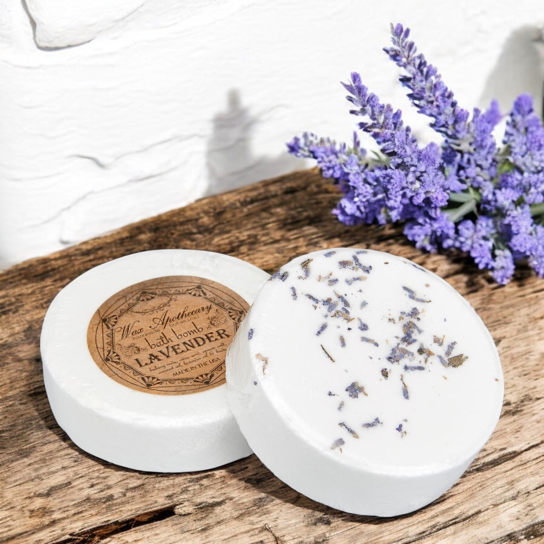 Two lavender-scented bath bombs on a wooden surface with a bouquet of lavender flowers.