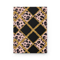 A notebook or journal with a patterned cover featuring black and pink leopard print, large black diamond sections, and a gold chain motif forming a lattice over the design, shown on a plain white background.