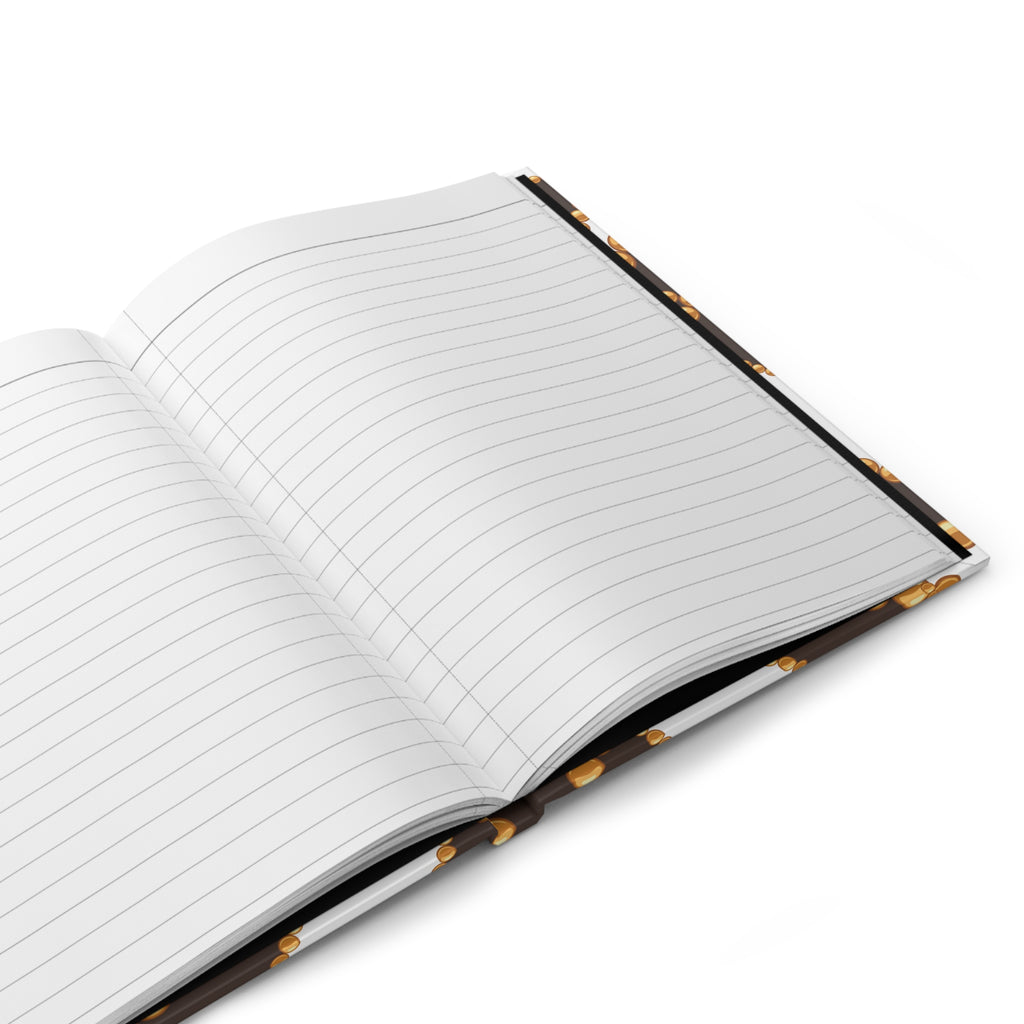 An open lined notebook with blank white pages, shown at an angle on a clean white background. The notebook has a dark brown or black cover with small gold decorative details along the spine.