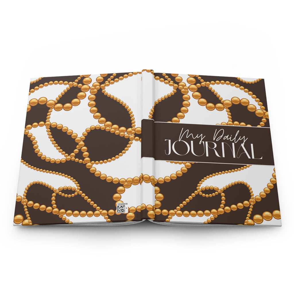 An open hardcover daily journal with a brown and white cover pattern featuring gold beaded loops, and a dark brown title band reading 'Mrs. Daily JOURNAL'.