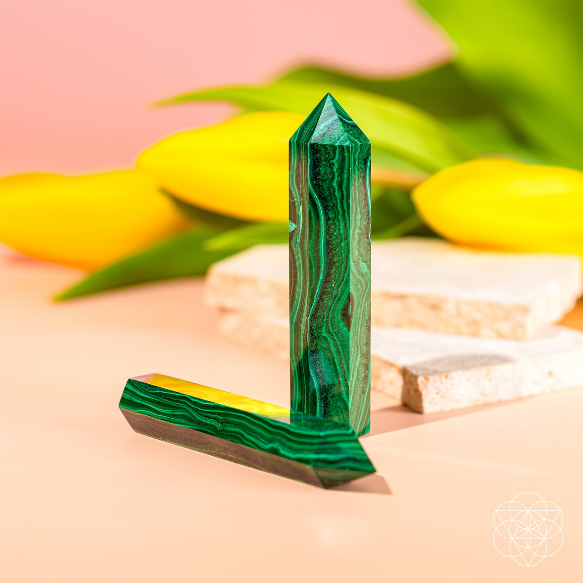 Green crystal on a pink surface with yellow flowers in the background