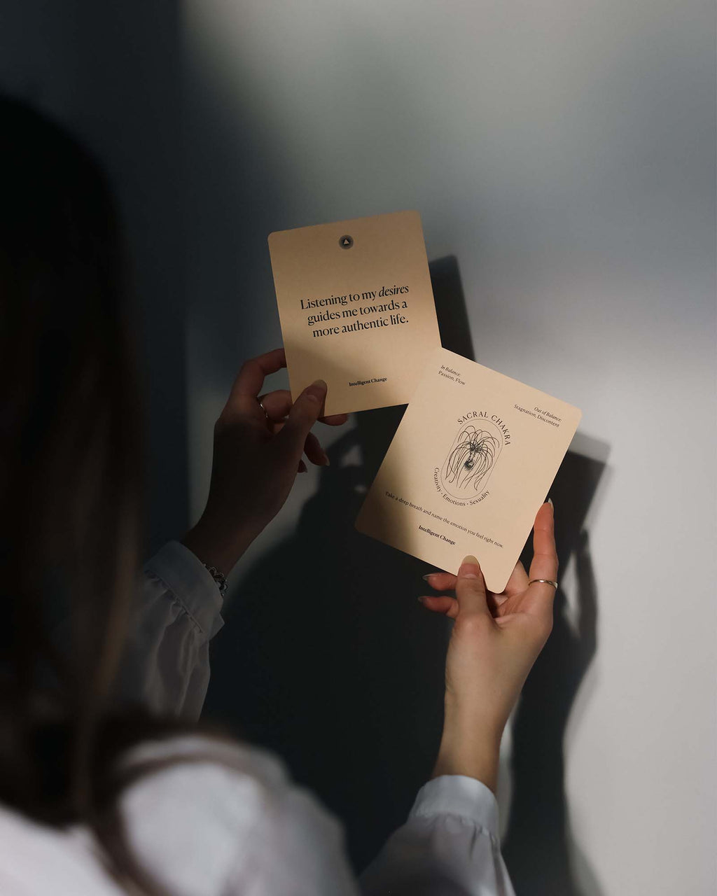 Person holding two cards with text and a logo, against a neutral background