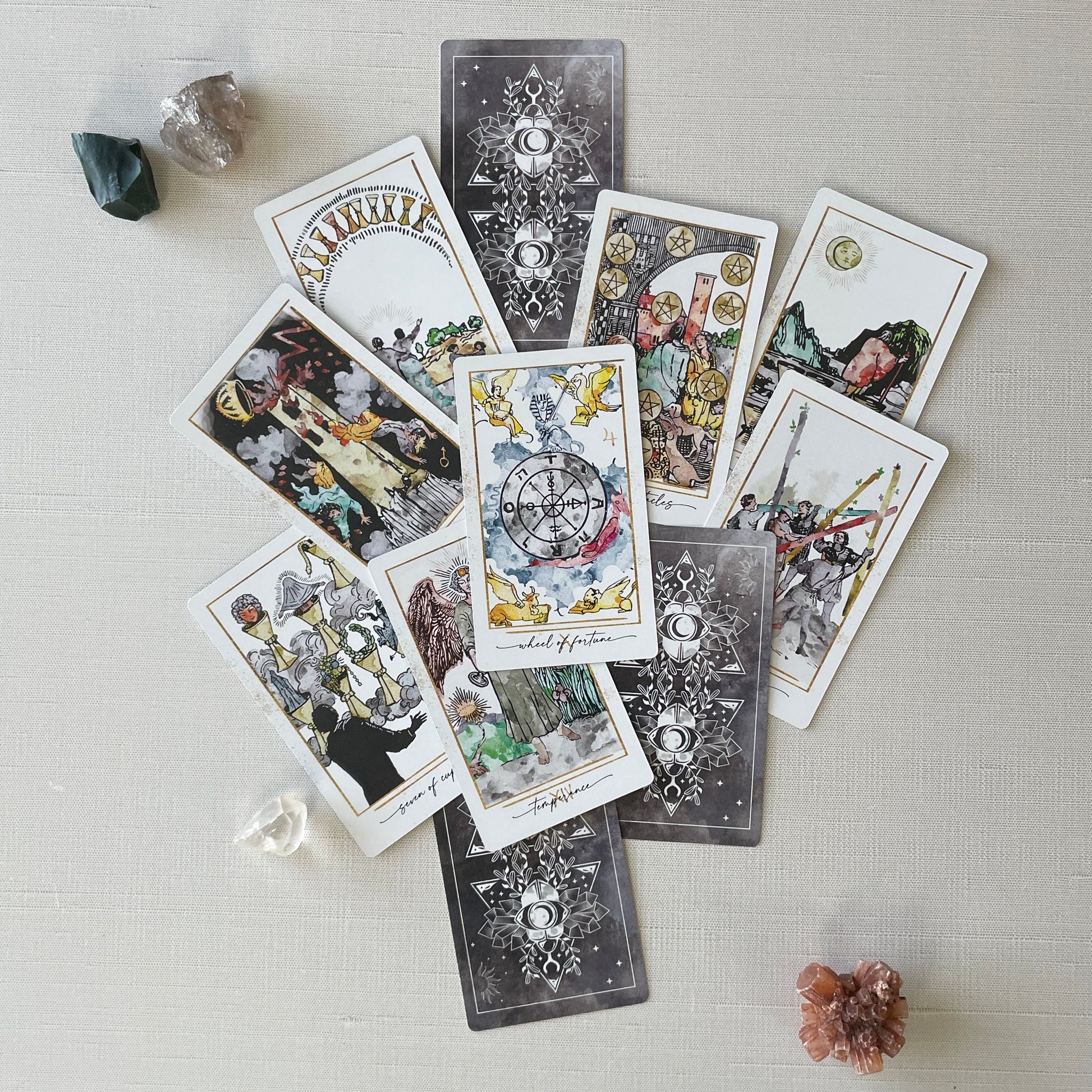 Collection of tarot cards on a light surface with crystals around