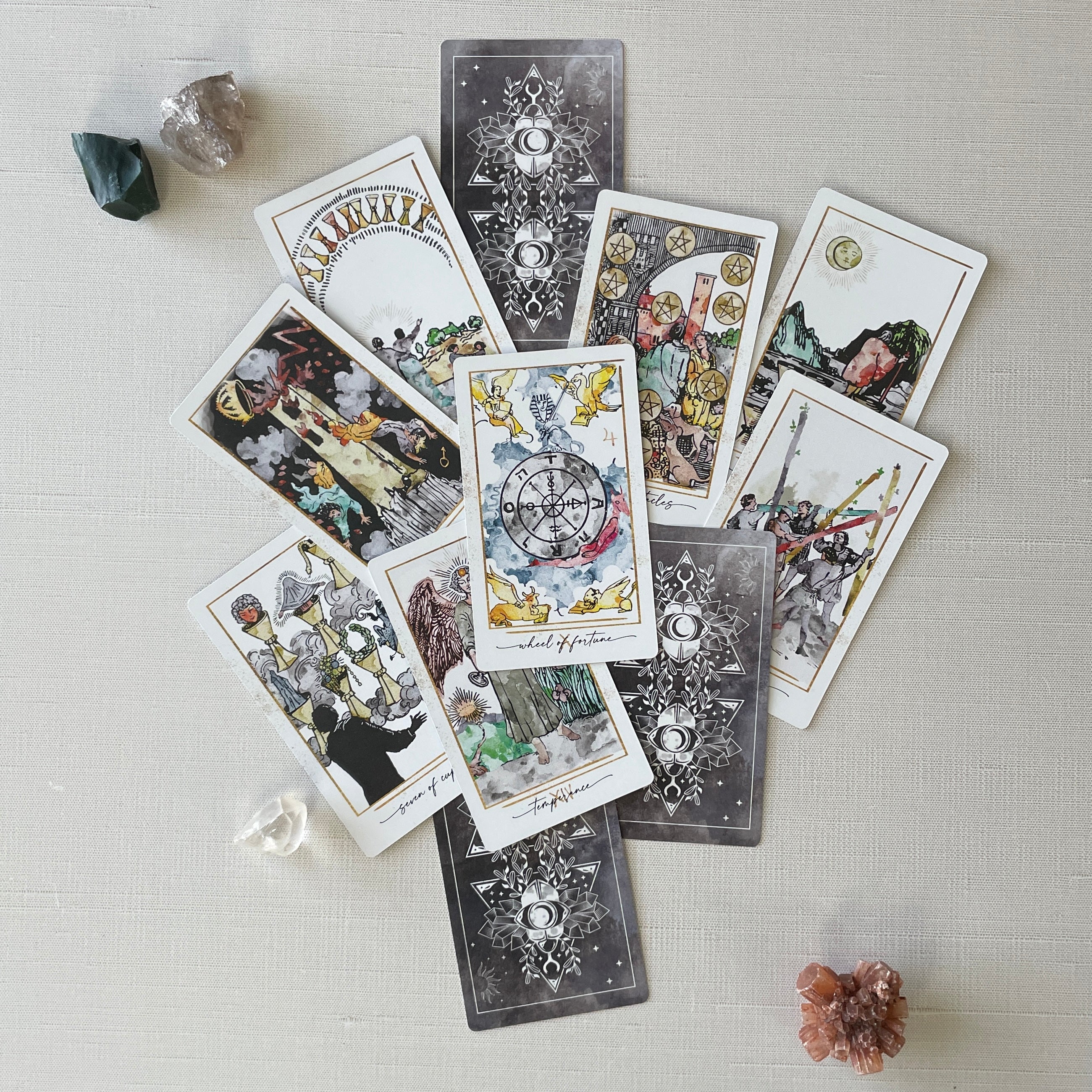 Collection of tarot cards on a light surface with crystals around
