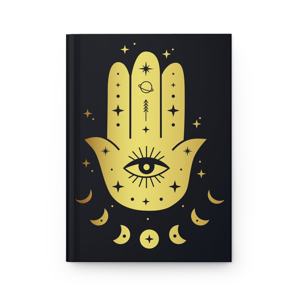 A hardcover notebook with a black cover featuring a large gold Hamsa hand design decorated with an all-seeing eye, stars, and crescent moons, shown on a plain white background.