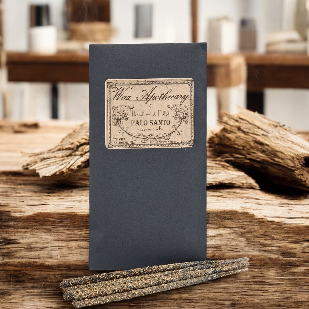 Wax Apothecary Palo Santo sticks on a wooden surface with a blurred background