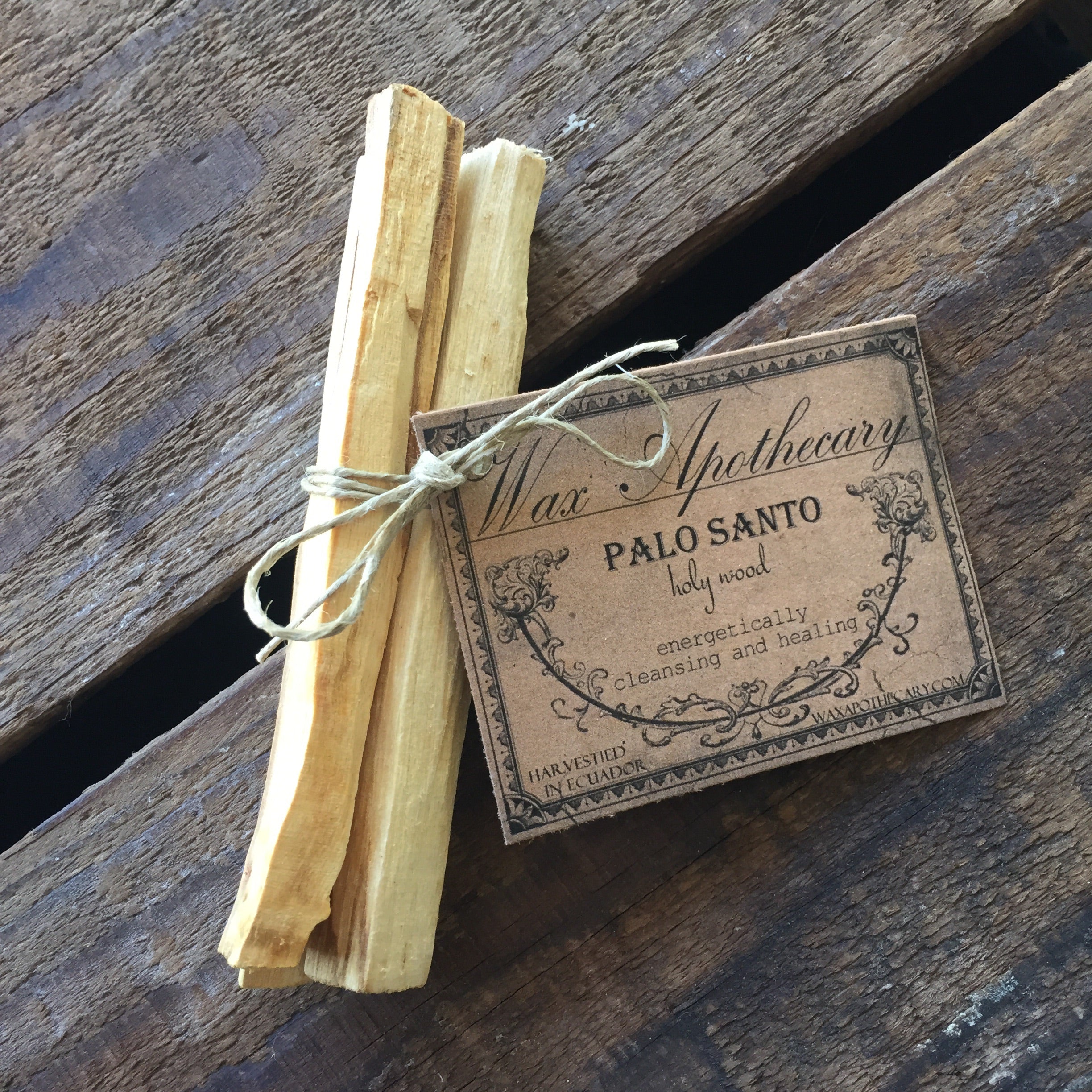 Palo Santo sticks tied with twine on a wooden surface with a label.