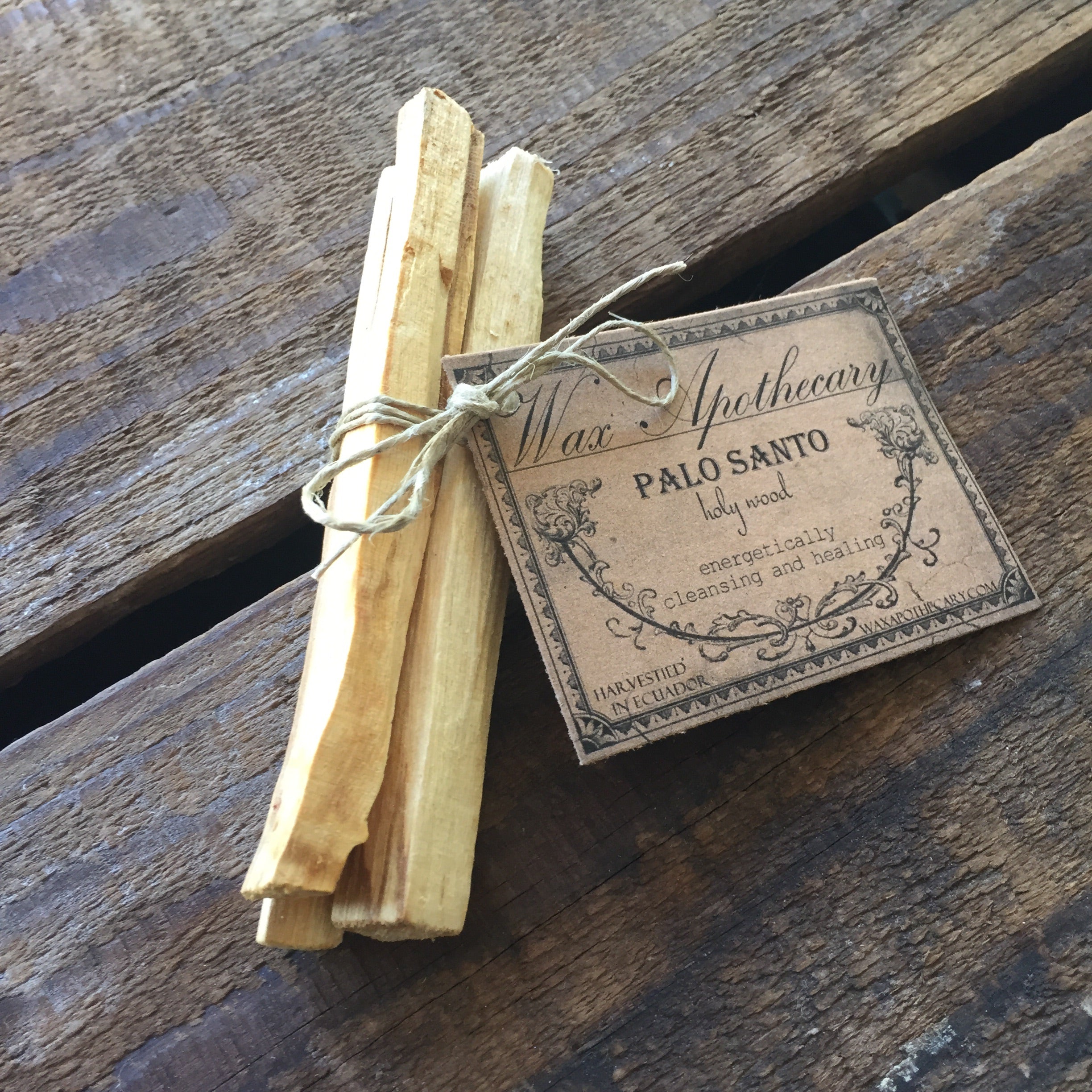 Palo Santo sticks tied with twine on a wooden surface with a label.