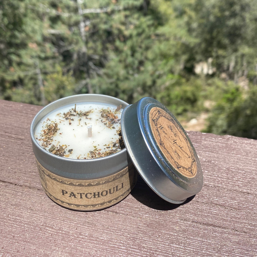 Patchouli candle in a tin with a natural label on a wooden surface with a blurred green background