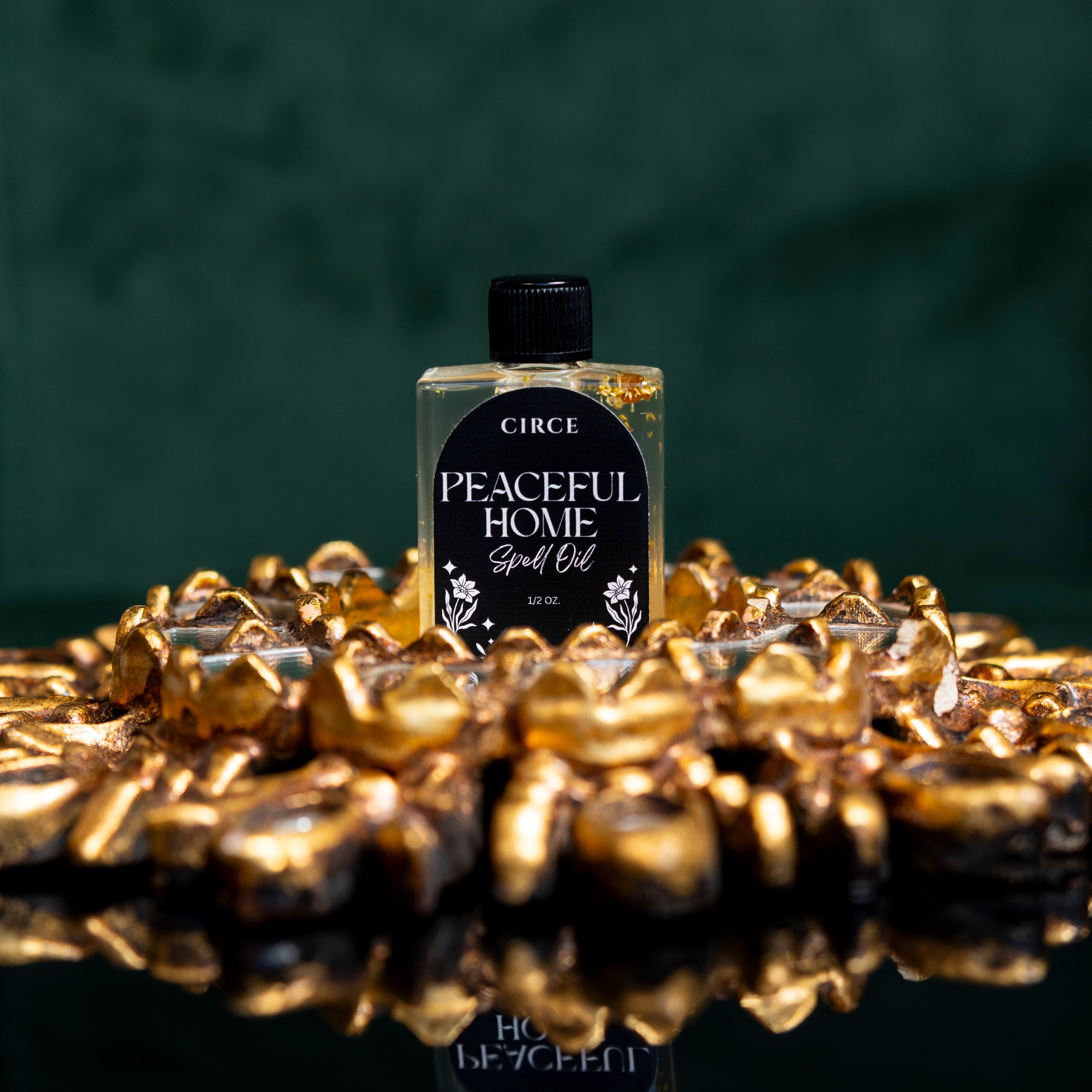 Circe Peaceful Home spell oil bottle on a decorative gold surface with a dark green background