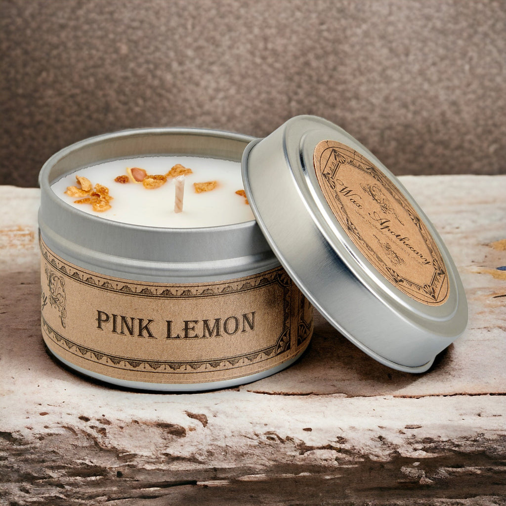 Candle in a tin labeled 'Pink Lemon' on a wooden surface