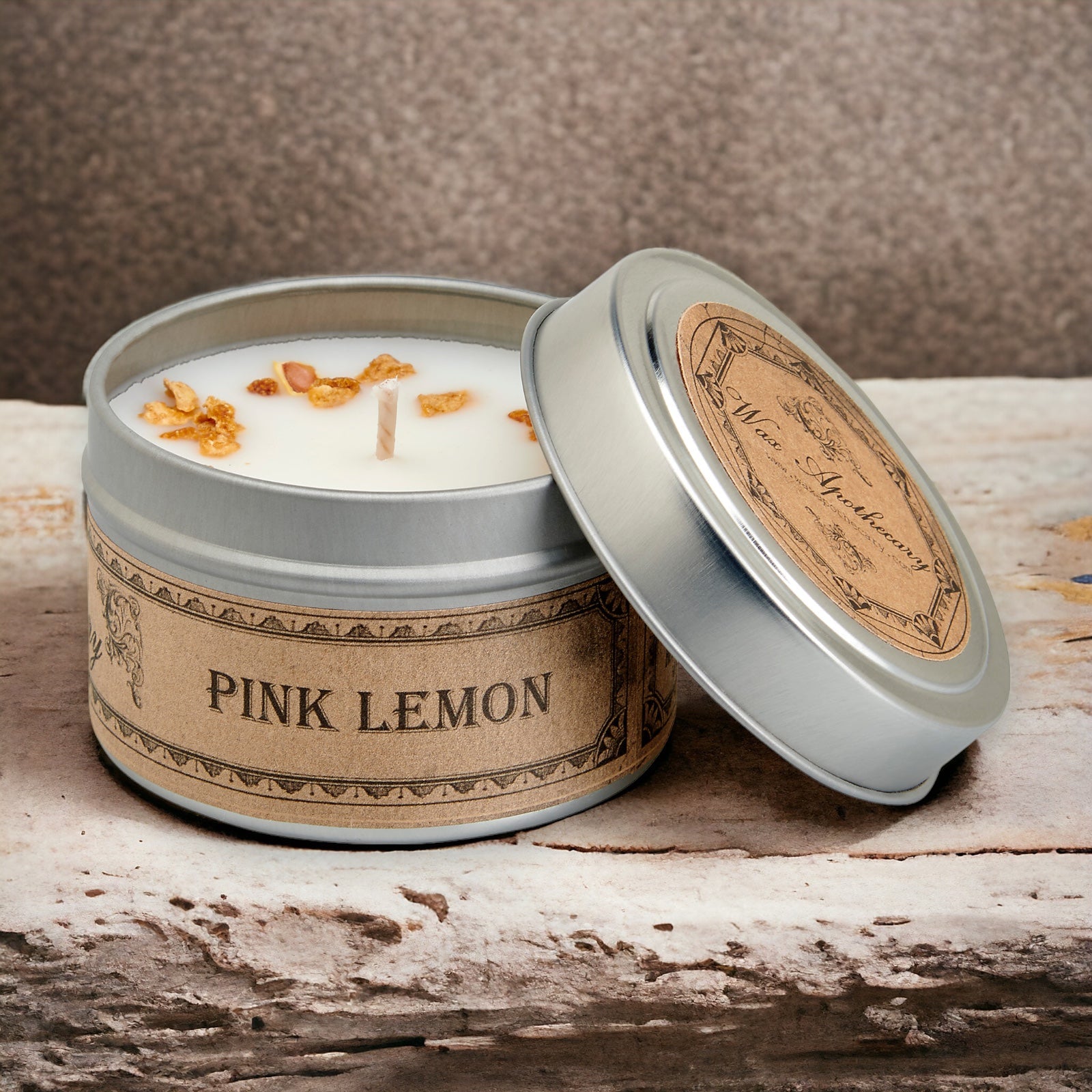 Candle in a tin labeled 'Pink Lemon' on a wooden surface