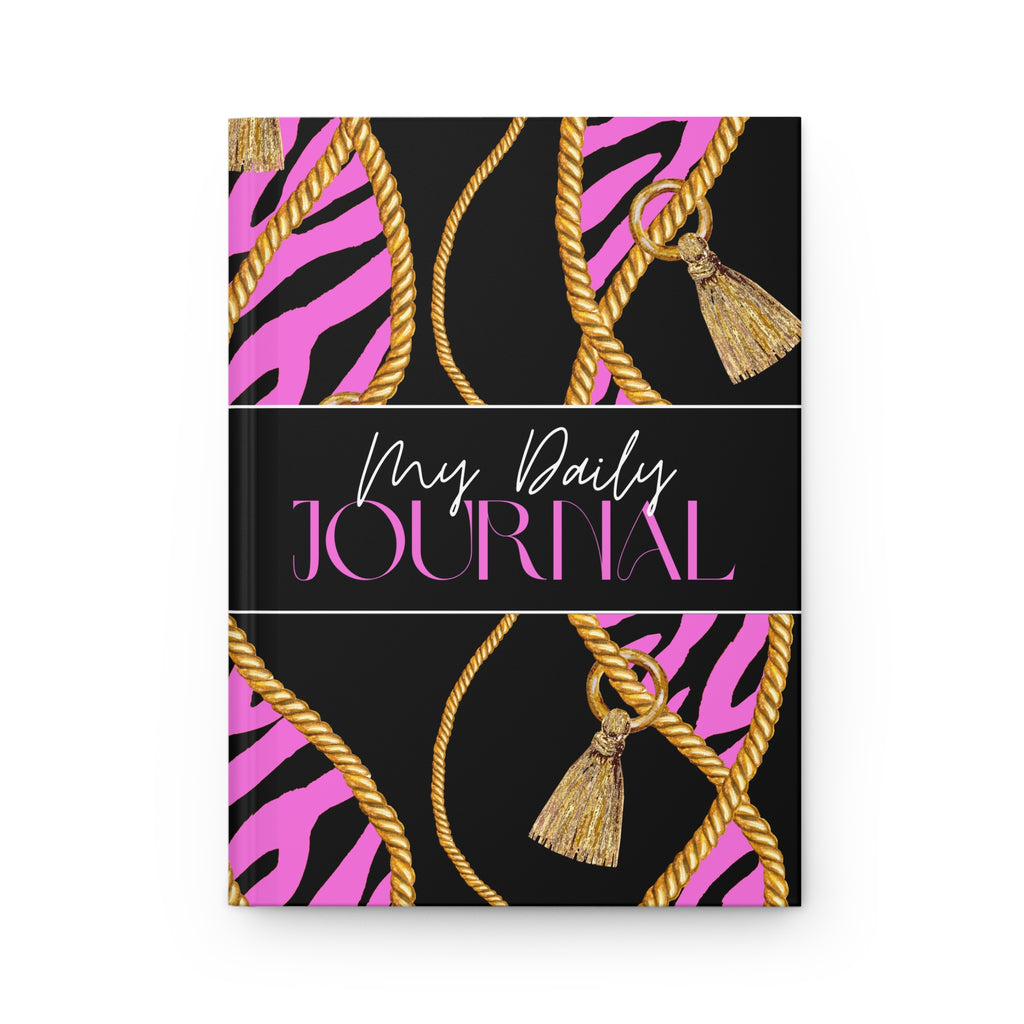 A hardcover daily journal with a black cover featuring pink zebra stripes, gold rope patterns, and gold tassels, with the text 'My Daily JOURNAL' printed across the center.