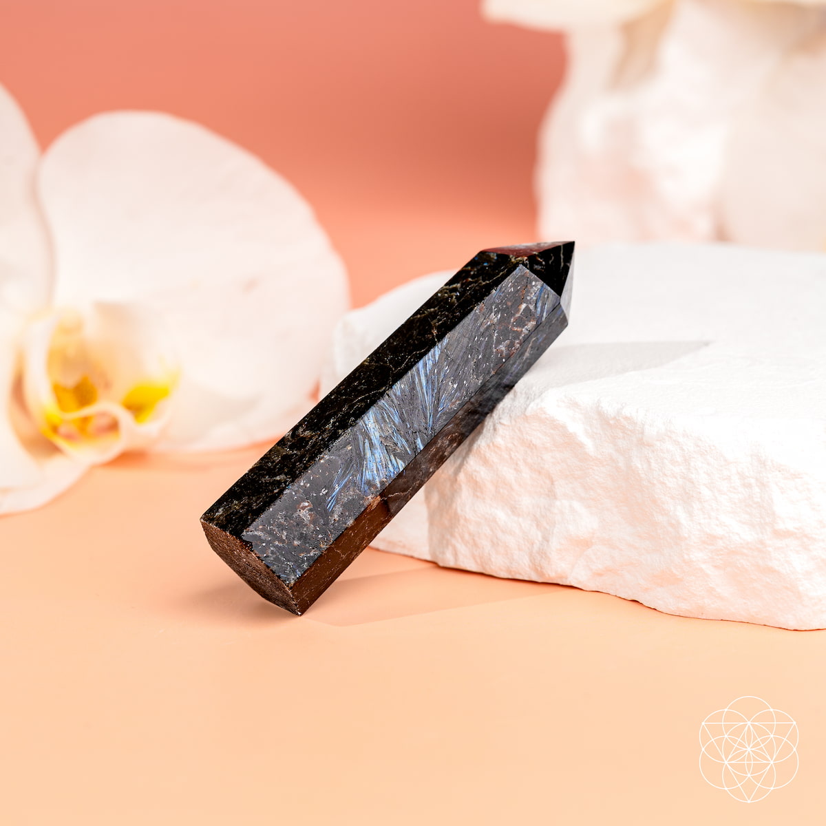 Crystal prism on a soft pink surface with a blurred flower in the background