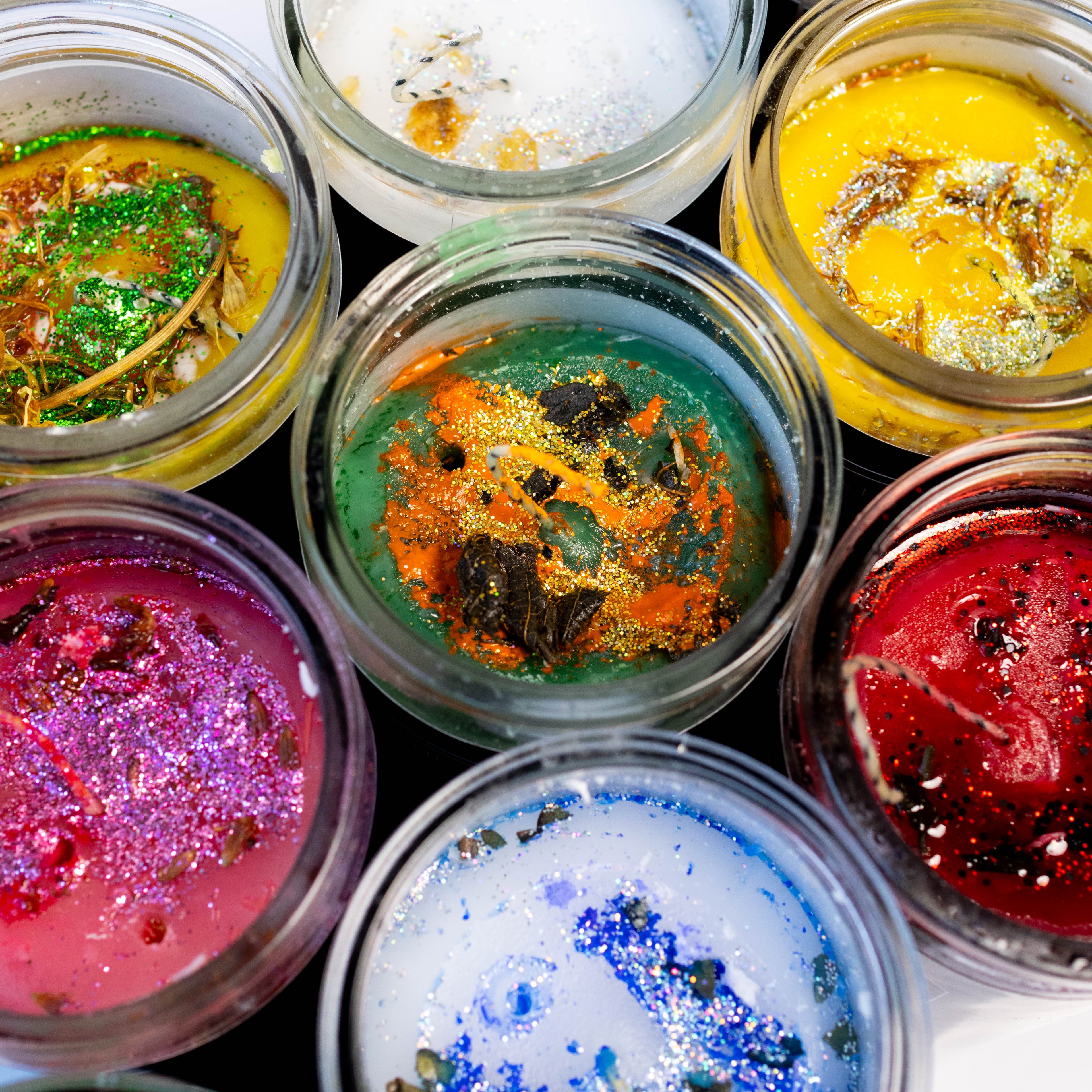 Assorted colorful powders in small glass jars on a black background