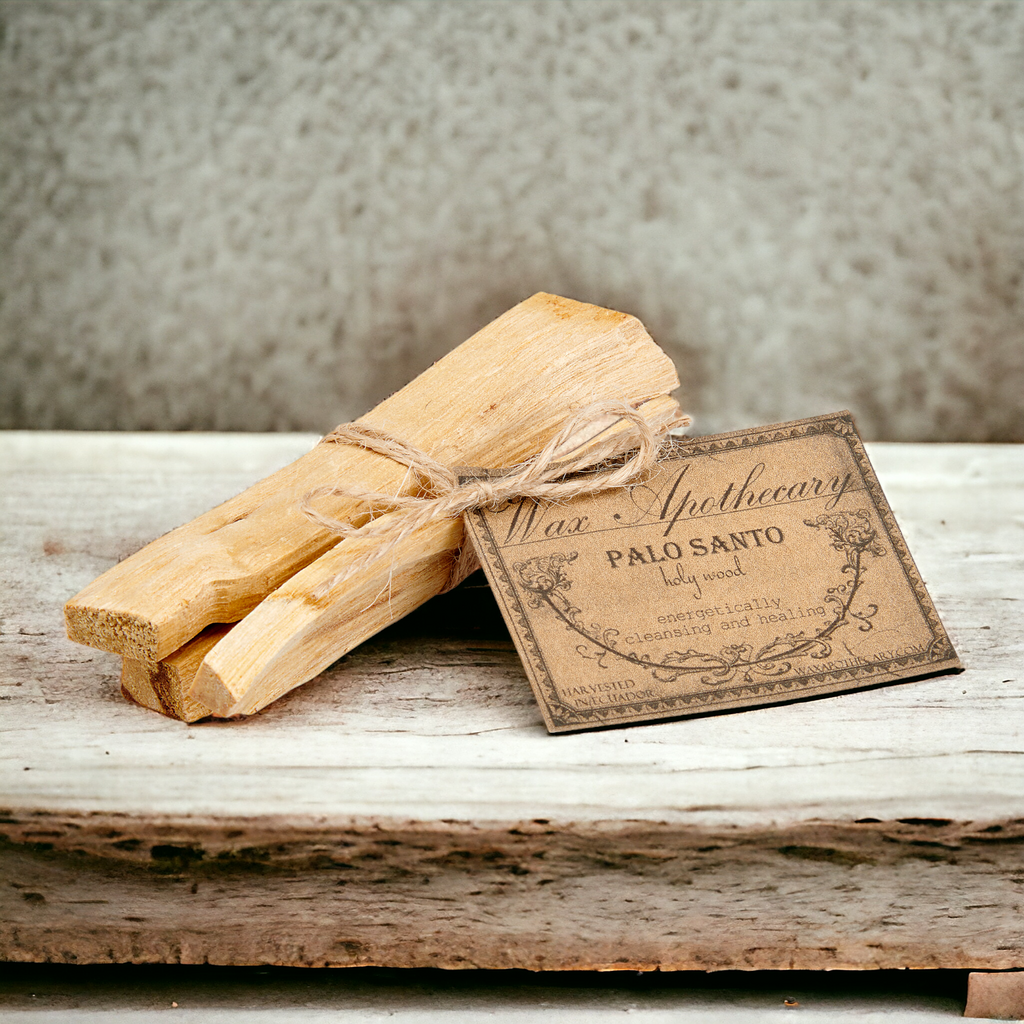 Two bundles of Palo Santo tied with twine on a wooden surface with a label.