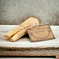 Two bundles of Palo Santo tied with twine on a wooden surface with a label.