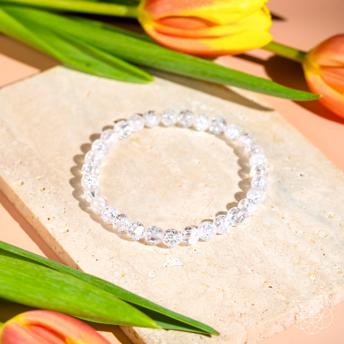 Clear beaded bracelet on a stone surface with tulips in the background