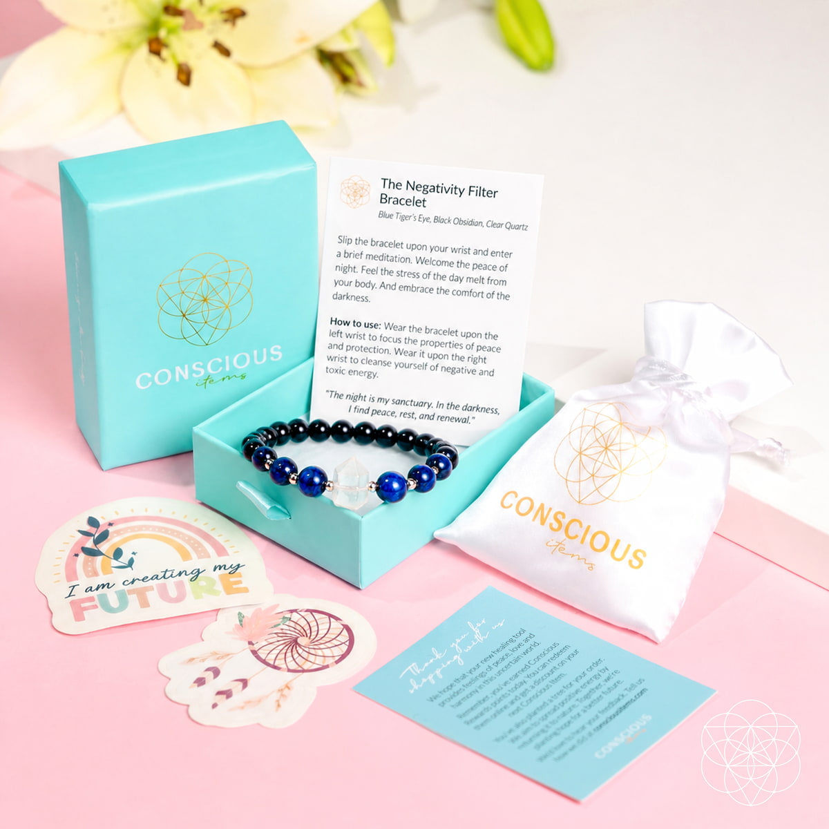 A Conscious Brand negativity filter bracelet set displayed on a pink background. The set includes a light blue gift box, a white drawstring pouch with gold branding, an instruction card, a small rainbow sticker, and a flower-shaped card.