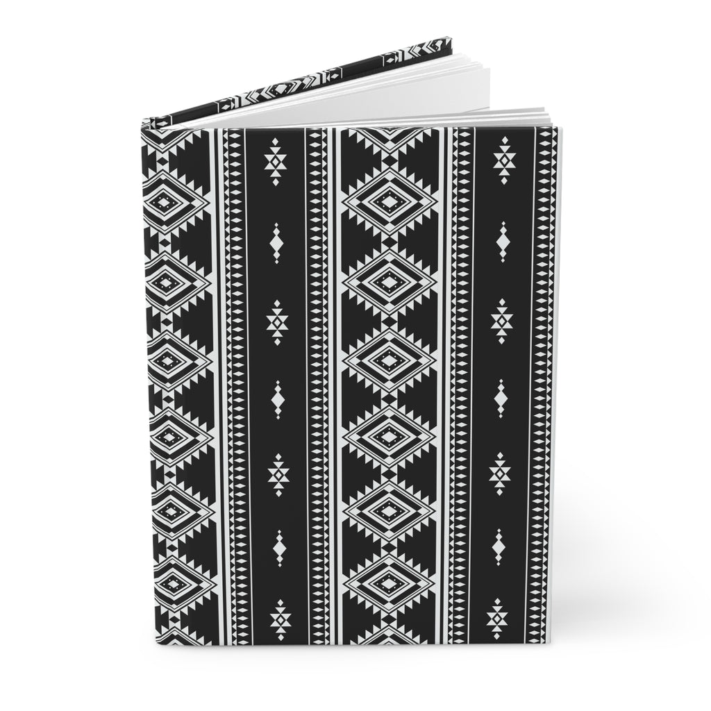 A hardcover notebook with a black and white geometric tribal pattern, shown standing upright on a white background.
