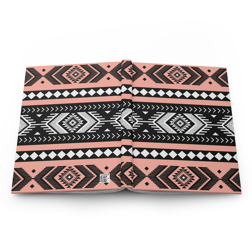 A hardcover notebook with a geometric Southwestern pattern in black, white, and coral pink, shown open on a plain white background.