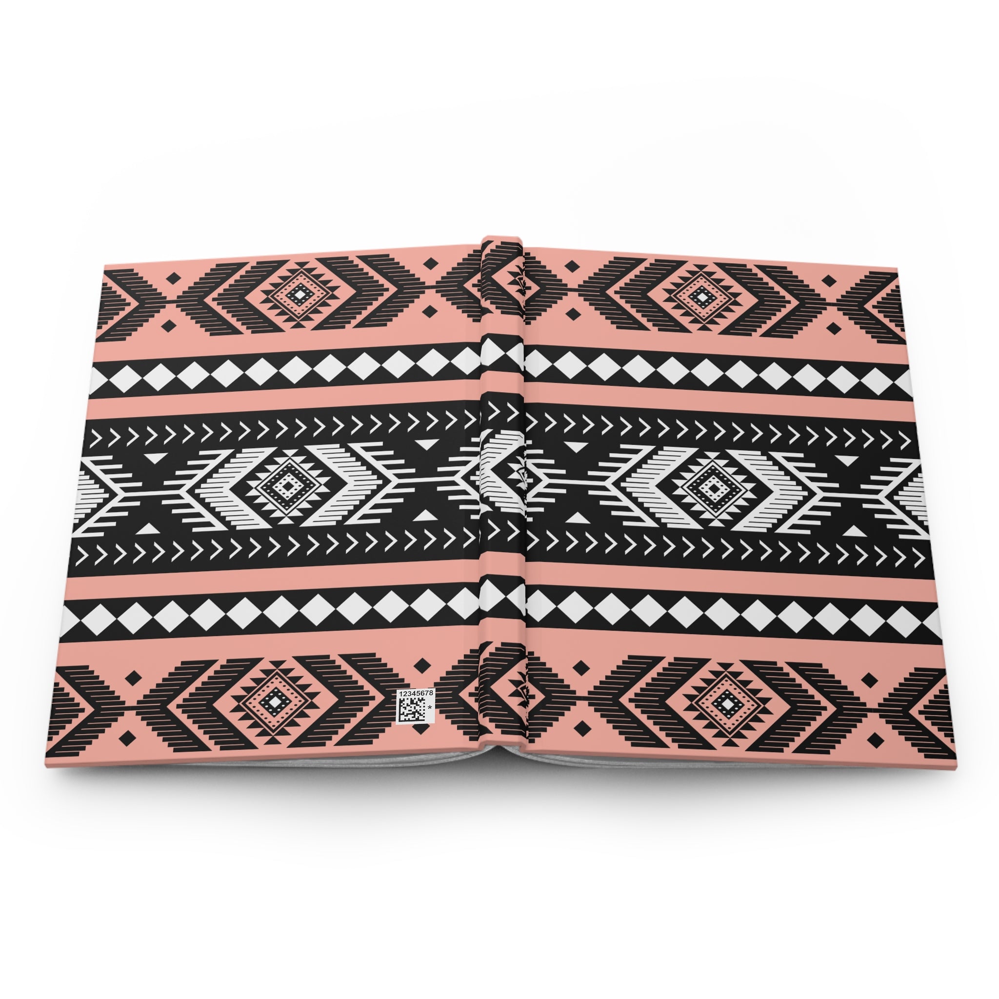 A hardcover notebook with a geometric Southwestern pattern in black, white, and coral pink, shown open on a plain white background.