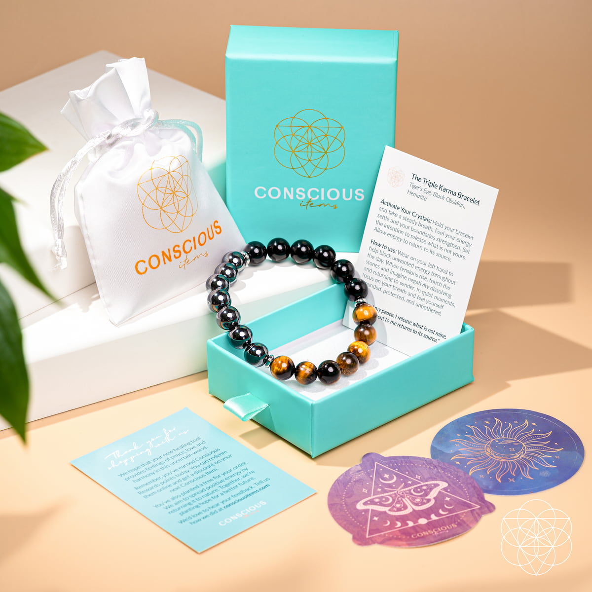 Bracelet with stones in a turquoise box labeled 'Conscious', with cards and decorative items on a beige surface.