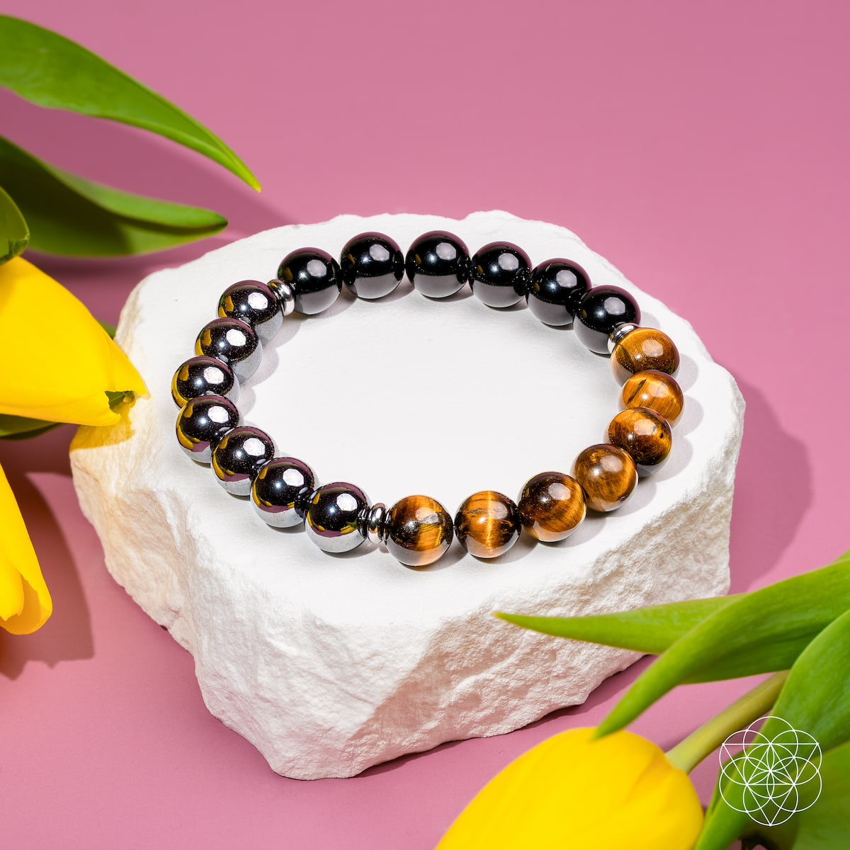Beaded bracelet on a white stone with yellow tulips on a pink background