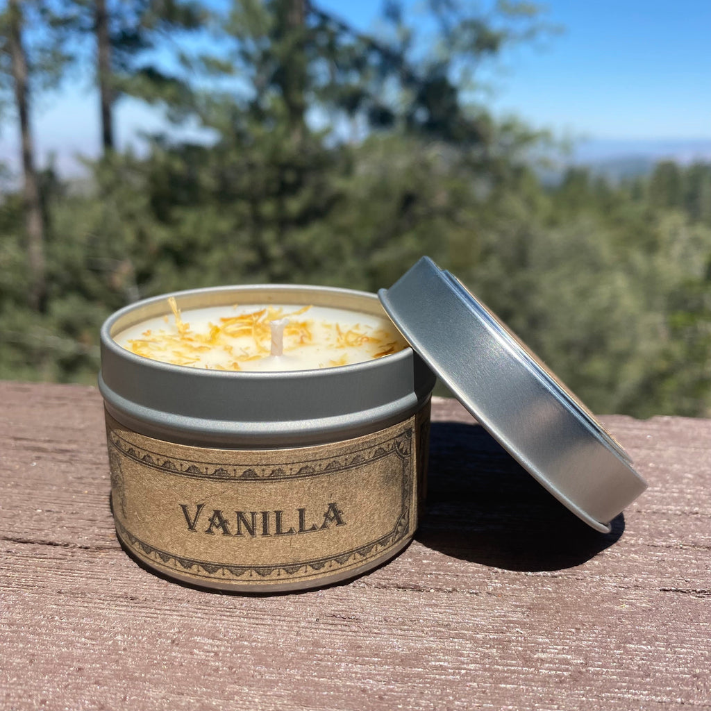 Vanilla candle in a tin with a lid on a wooden surface, outdoors.
