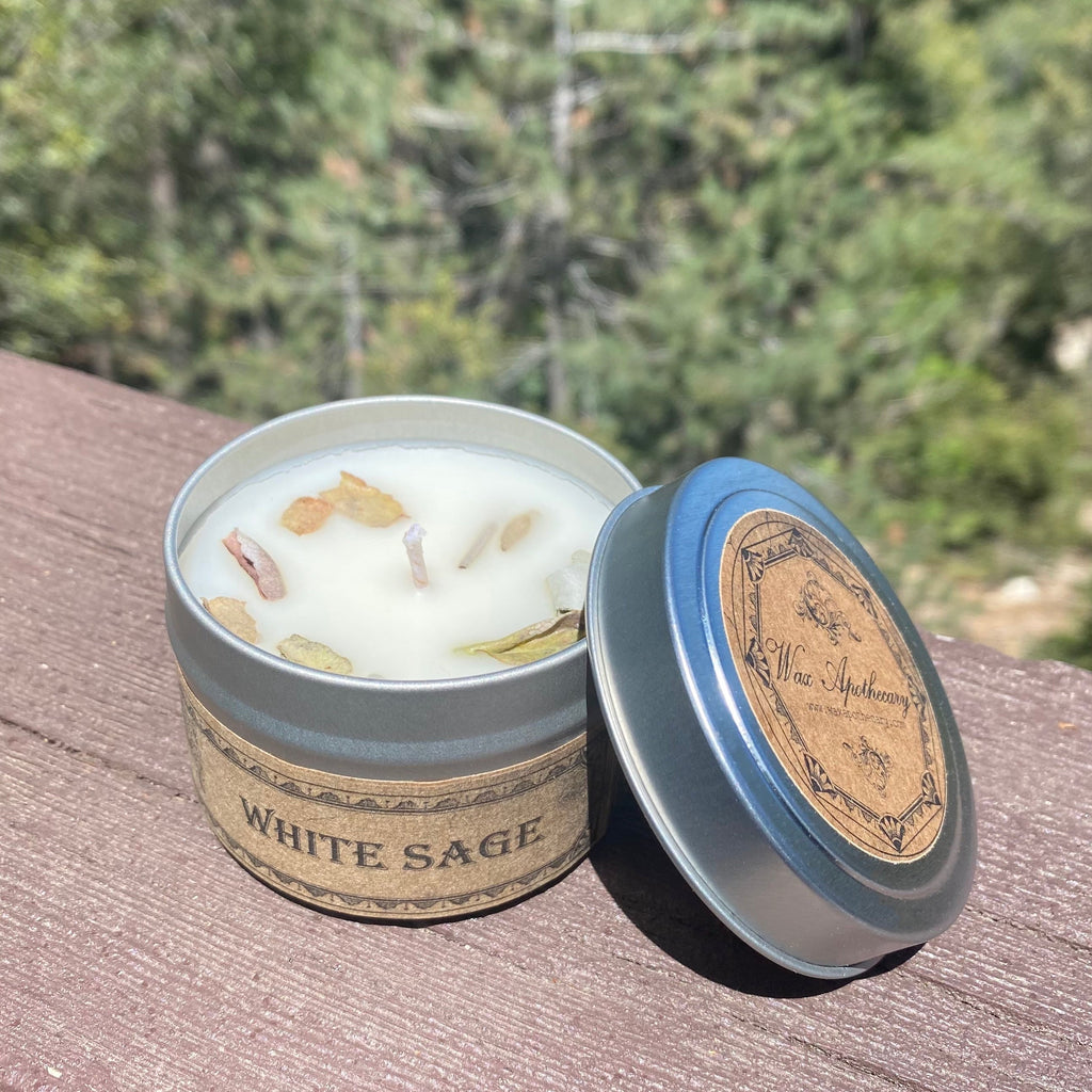 White sage candle in a tin with a wooden lid on a wooden surface with a blurred natural background