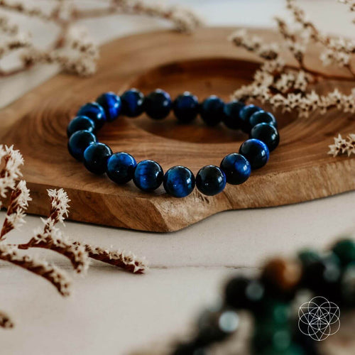 Blue beaded bracelet on a wooden surface with dried plants