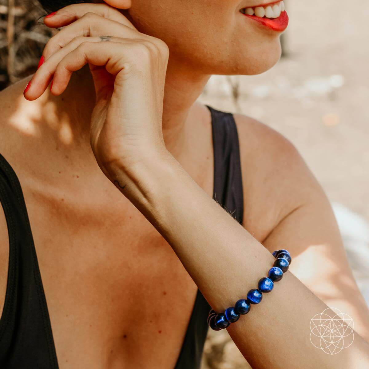 Woman wearing a blue beaded bracelet on her wrist with a blurred background