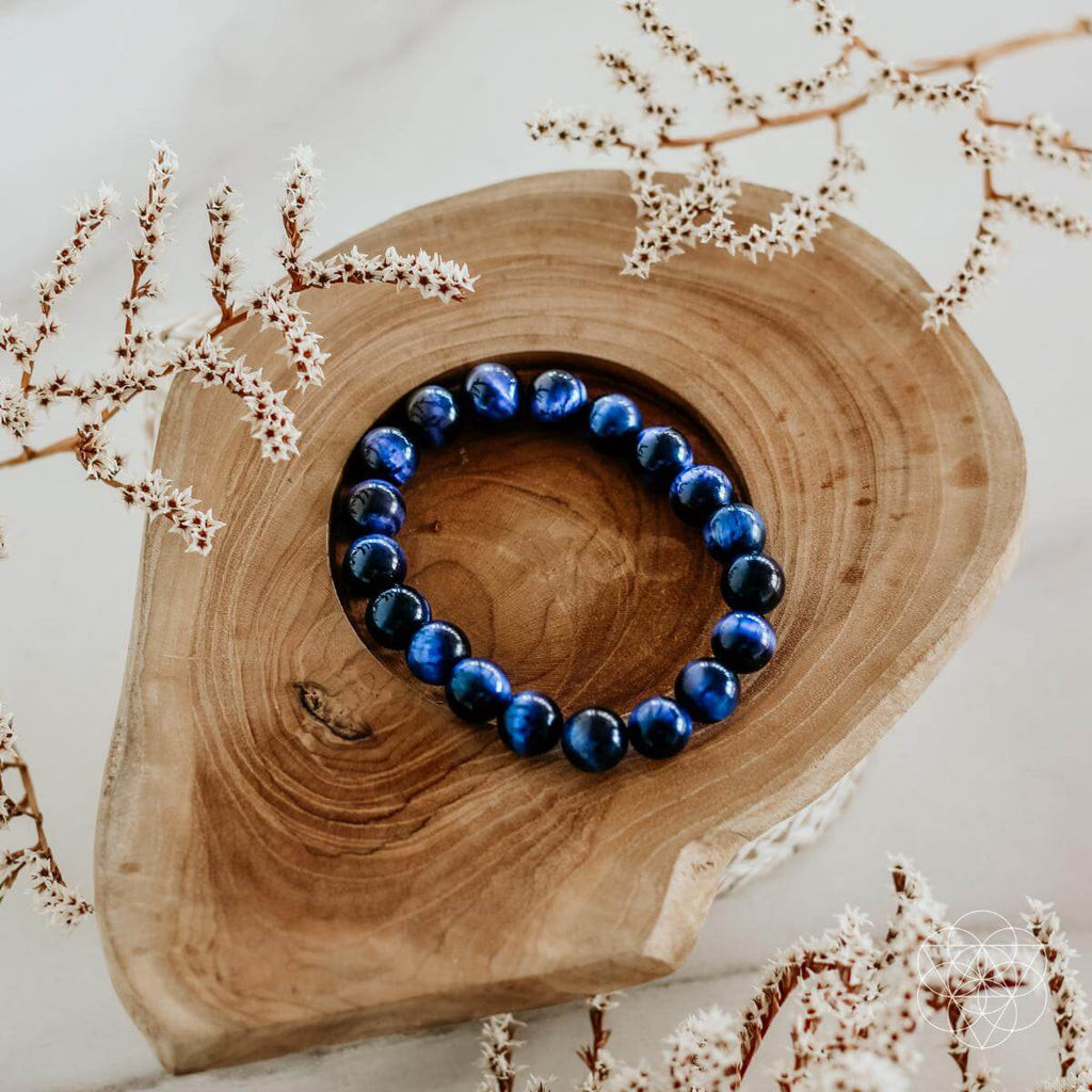 Blue beaded bracelet on a wooden surface with decorative branches.