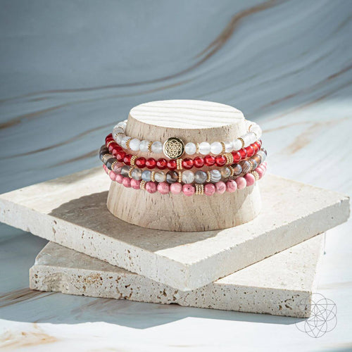 Stack of beaded bracelets on a wooden block with a neutral background