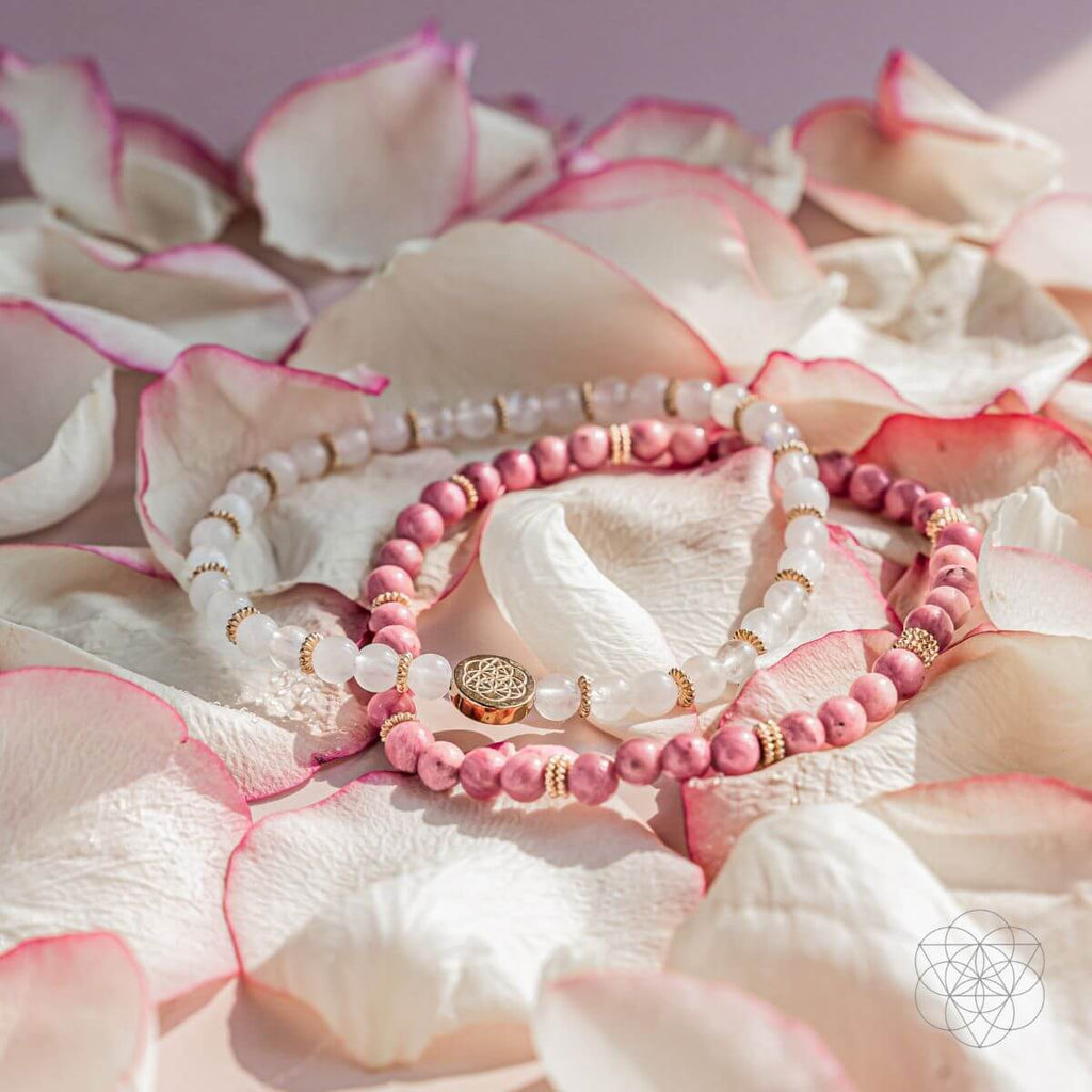 Set of pink and gold beaded bracelets on white and pink flower petals