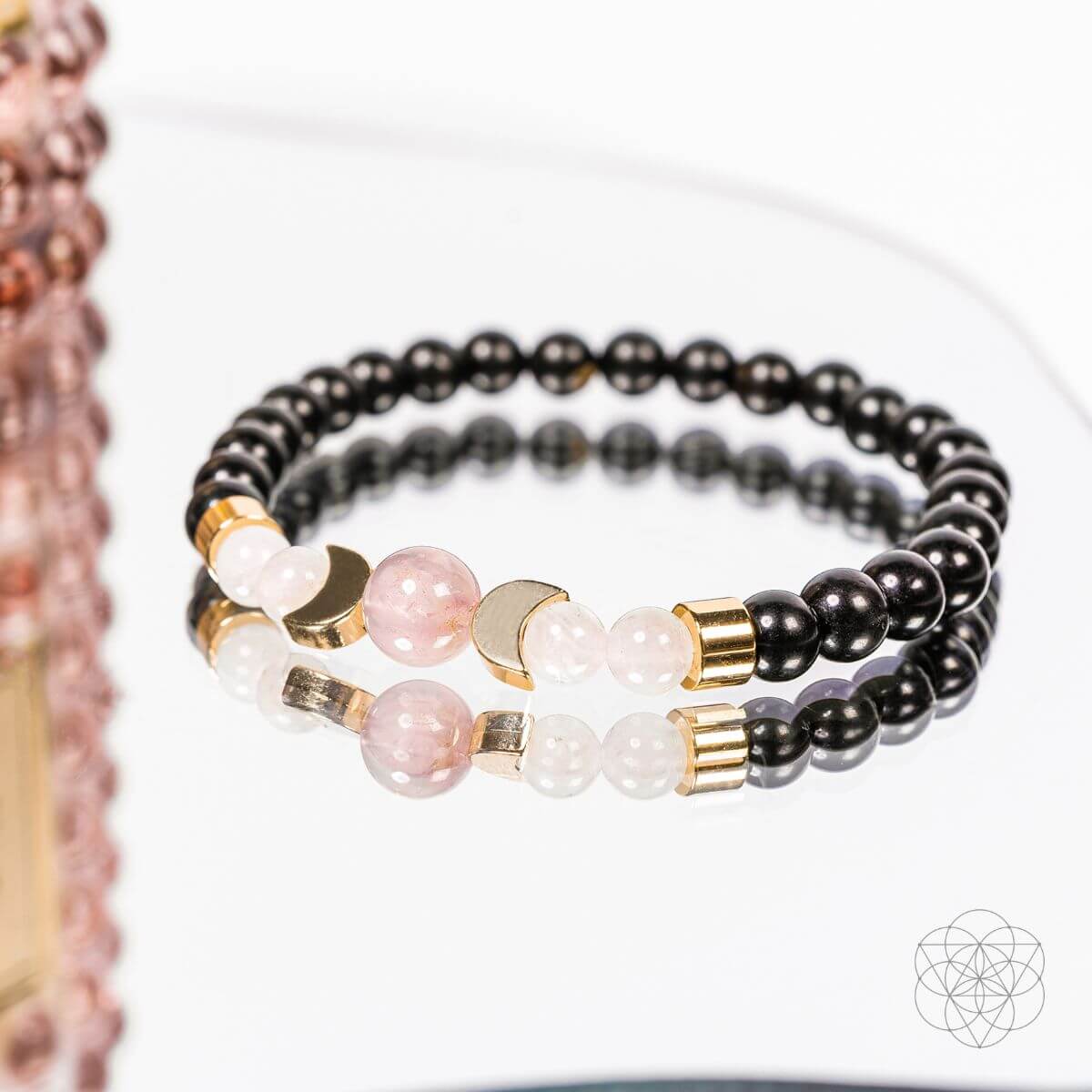 Stack of black and pink beaded bracelets on a white background