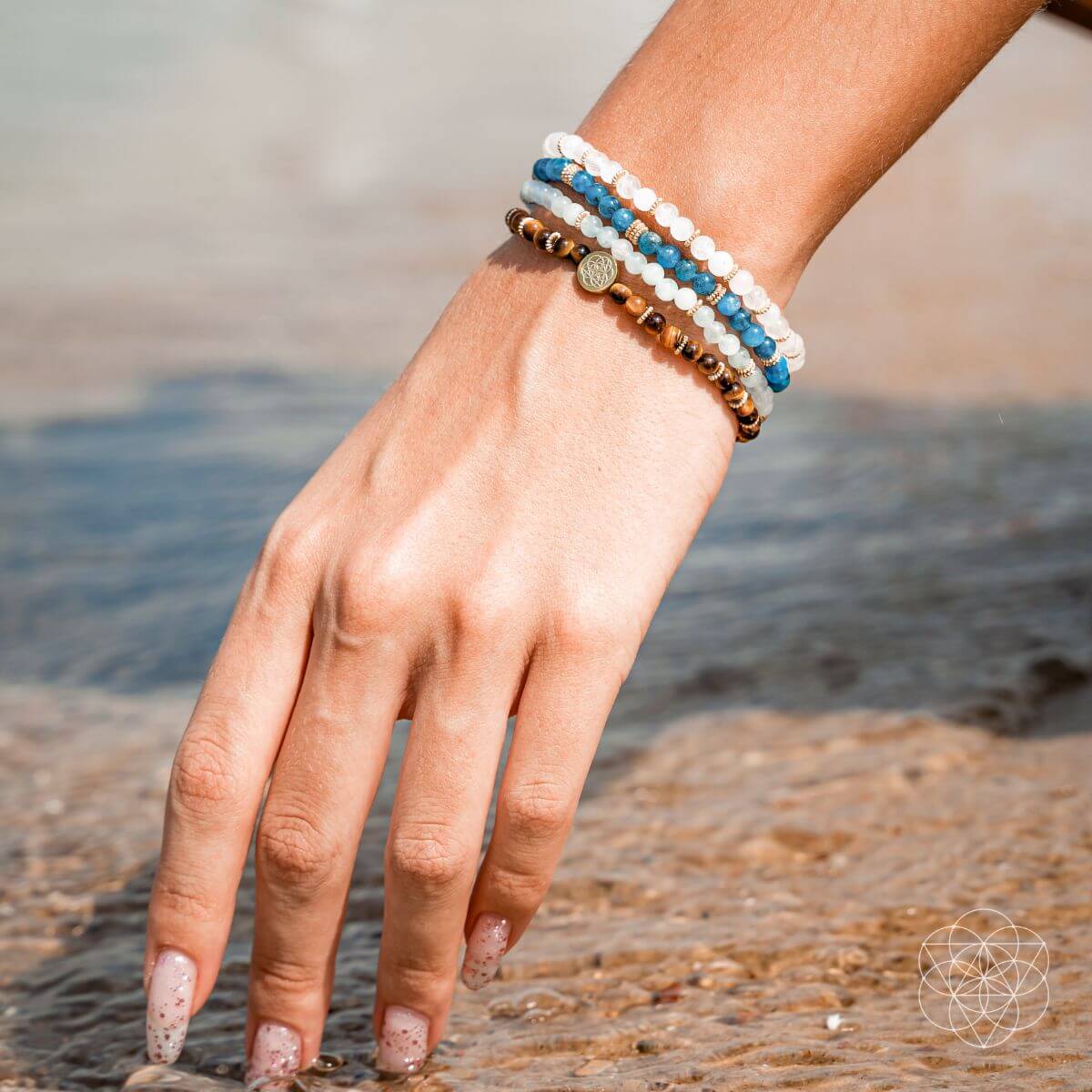 Hand wearing multiple bracelets with a blurred natural background