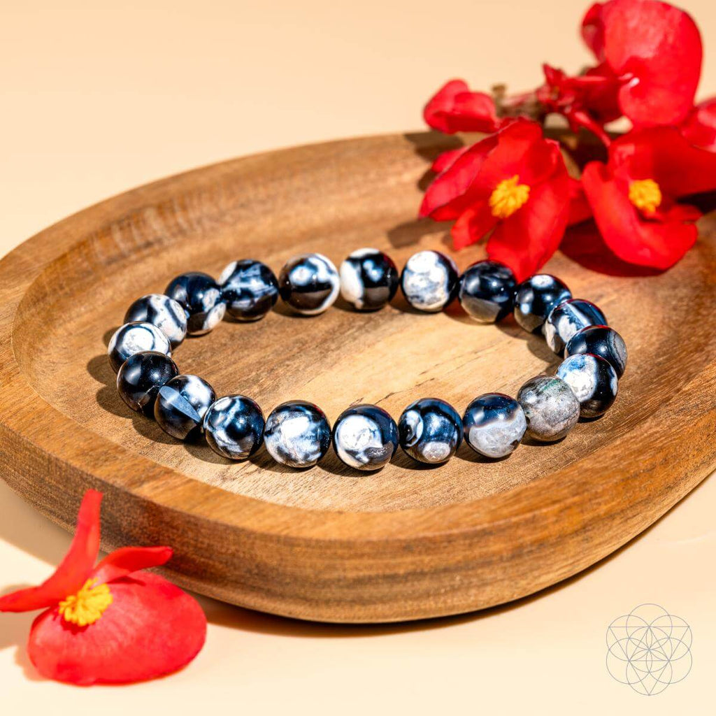 Beaded bracelet on a wooden plate with red flowers