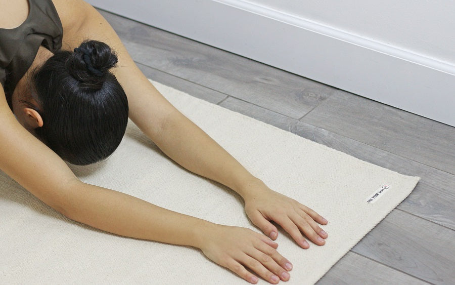 Person practicing yoga on a beige mat with a neutral background