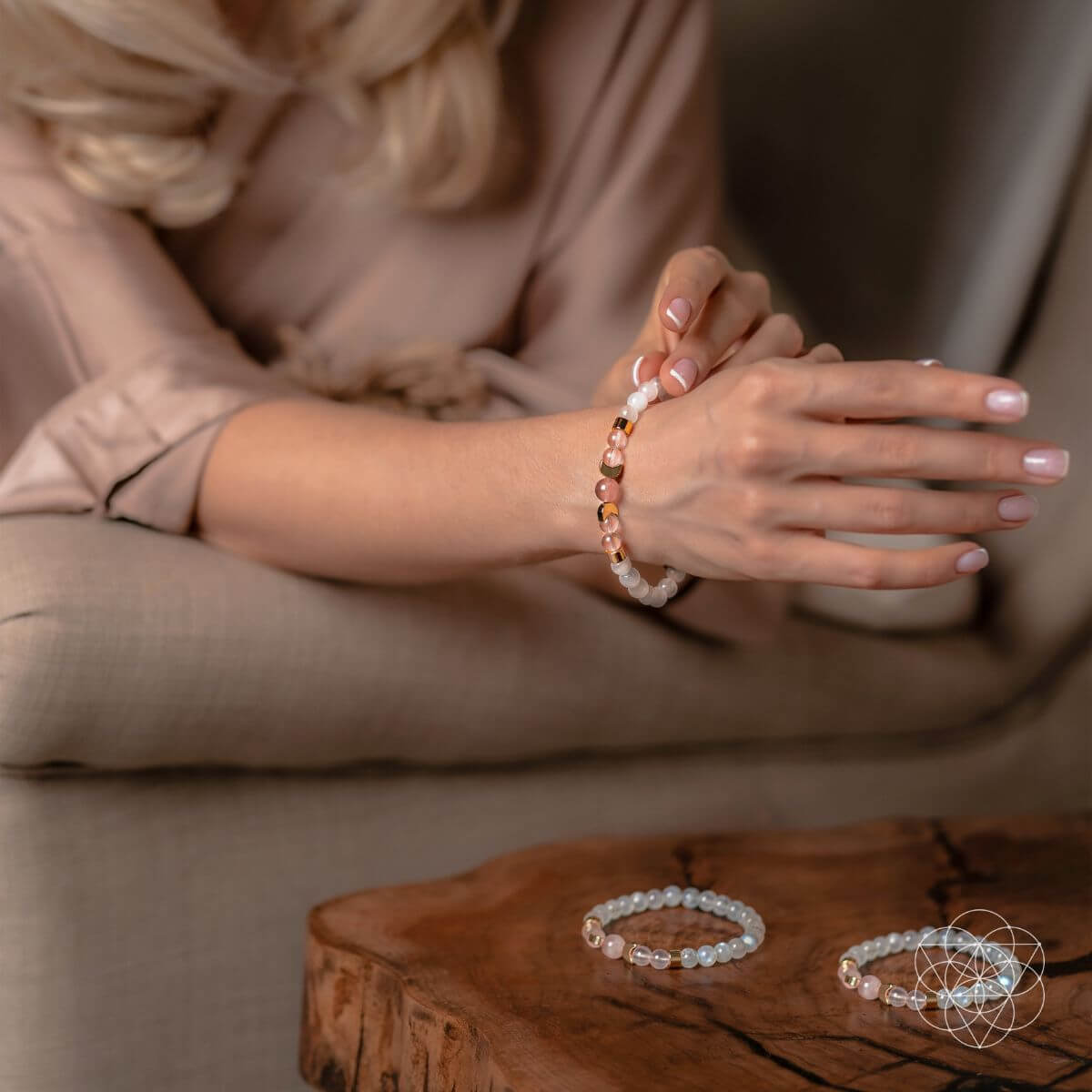 Person wearing a bracelet with a cup, with additional bracelets on a wooden surface.