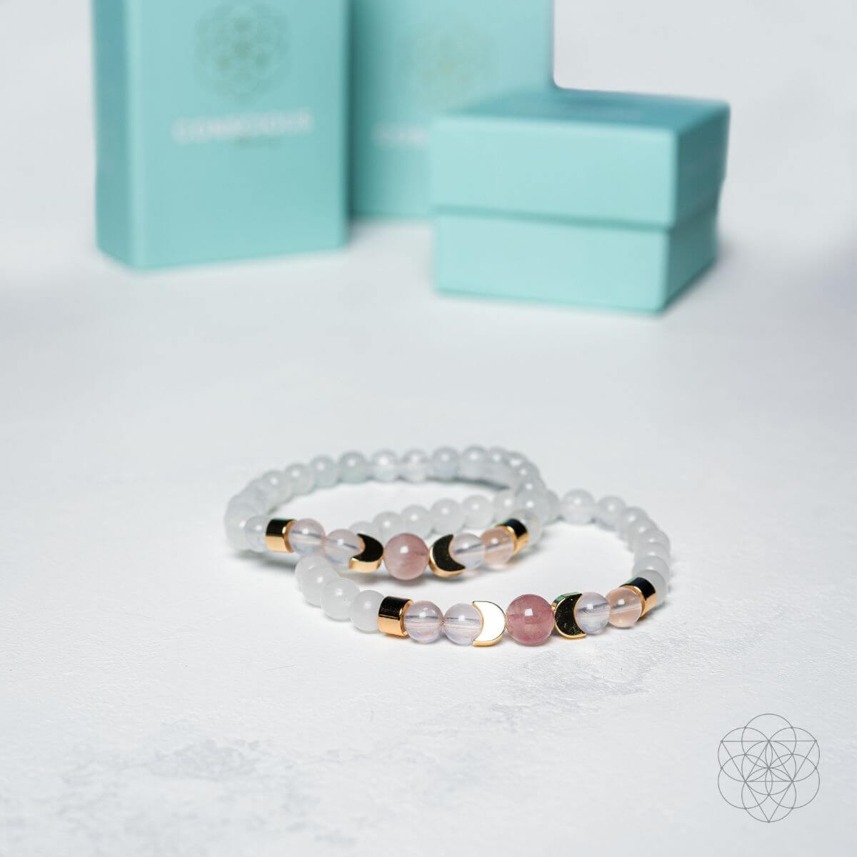 Two beaded bracelets with gold accents on a light gray background with a turquoise box.
