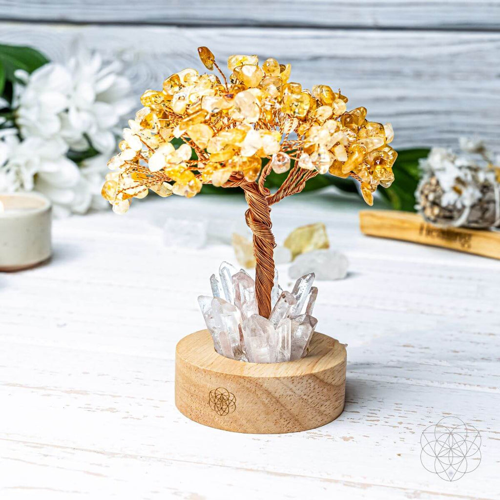 Decorative crystal tree with yellow beads on a wooden base, set against a light background.