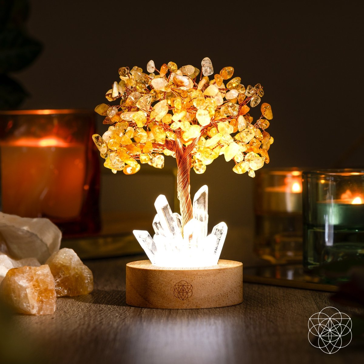 Decorative crystal tree lamp with glowing base on a wooden surface, candles in the background.