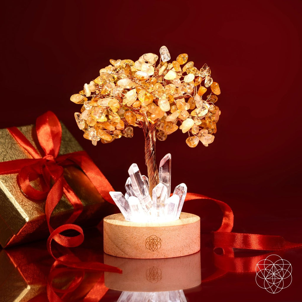 Decorative crystal tree with gift box on a reflective surface against a red background